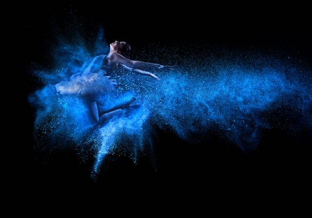 A ballet dancer leaping in a cloud of chalk