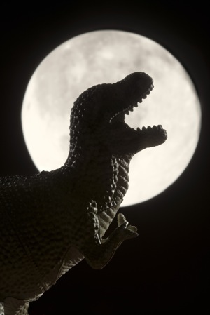 A dinosaur roars in front of the moon