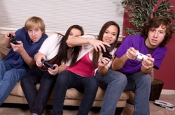 gamers on a sofa, leaning over as they press their controllers