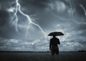 a man holding an umbrella under a cloudy sky with lightning