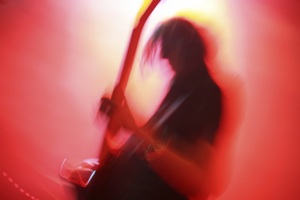 a blurry guitarist in red stage light